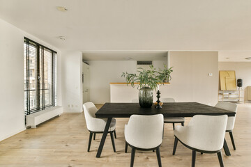 A sleek and contemporary dining room featuring a stylish table with chairs and large windows that fill the space with natural light.