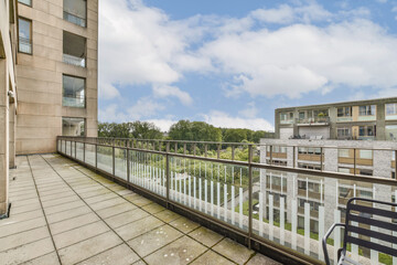Fototapeta premium A spacious balcony featuring a contemporary design overlooking lush greenery and blue skies, perfect for relaxing and enjoying outdoor living.