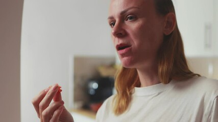 Cheerful female tasting delicate appetizers, indulging culinary moments near bright kitchen window, expressing pure gastronomic delight with every bite
