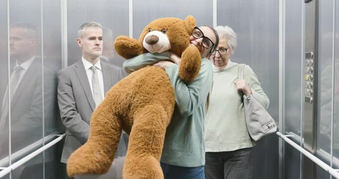 Happy woman holding a huge teddy bear in the elevator