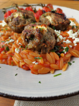 Greek Kritharaki pasta with Bifteki, roasted tomatoes, and feta cheese