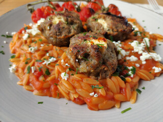 Greek Kritharaki pasta with Bifteki, roasted tomatoes, and feta cheese