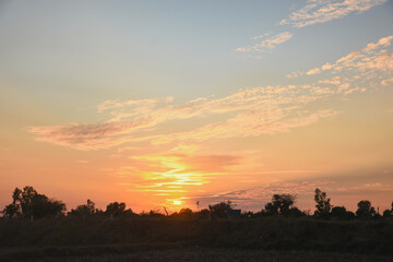 the serene and peaceful moment of sunset. The sun's warm orange and yellow hues spread across the horizon, blending seamlessly into the deep blue sky.