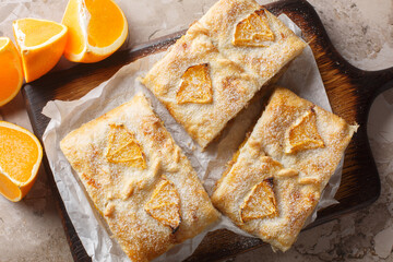 Homemade orange puff pastry pie with walnuts, raisins and fresh fruits close-up on wooden board on...