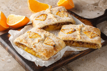 Orange pie with walnuts, raisins and fresh fruits filling close-up on wooden board on table. Horizontal