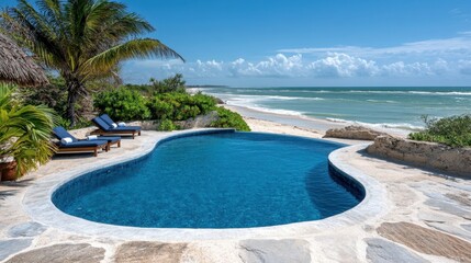 Obraz premium Serene coastal escape with turquoise pool palm trees and ocean view perfect for relaxation and vacation getaway under blue sky