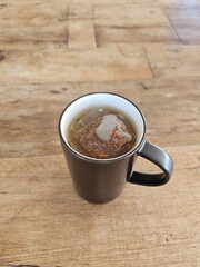 Black ceramic mug with a tea bag, warm beverage concept. Steam rising, cozy atmosphere, perfect for relaxation and comfort