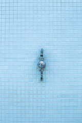 Texture of small blue tiles. Wall and construction materials, masonry. Pool shower on a background of small tiles.