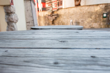 Old wooden table in street cafe - close-up of vintage wooden table with worn finish in urban environment, copy space,