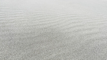 Beach sand background. Sand is naturally cooler coloured, Pacific seaside beach in Peru. Beautiful wave pattern due to strong wind.
