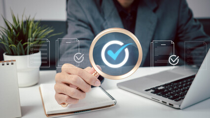 A person is holding a magnifying glass with a check mark over a laptop screen. system, innovation, typing, technology, iot, future, job, social, management, marketing.
