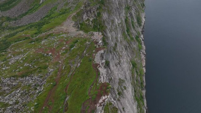 Drone footage of Segla rocky mountain and a lake behind clouds on Senja Island in Norway