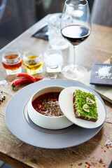 Borscht soup. Black Angus beef, beetroot, sour cream, toasted bread with smalec in a bowl. Delicious healthy food closeup served for lunch on a table in modern gourmet cuisine restaurant