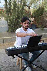 Fototapeta premium Boy Pianist Plays The Keyboard In An Outdoor Garden For A Private Party