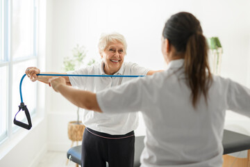 physiotherapist helping senior woman in clinic. Elderly woman undergoing physiotherapy treatment for injury