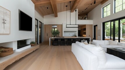A large living room with a fireplace, a flat screen TV, and a kitchen. The room is very spacious and has a modern design
