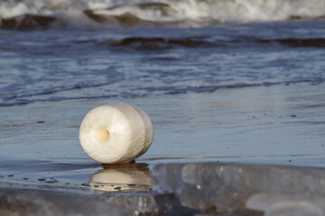 
white buoy on the beach with the sea in the background.