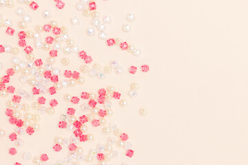 Different acrylic beads scattered on a beige background with place for text.