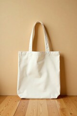 A simple off-white cotton tote bag rests against a neutral backdrop, showcasing its versatile design and minimalist aesthetic on a light wooden floor.