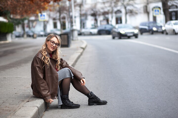 Fototapeta premium a beautiful stylish girl dressed in urban style of clothes walks around the city in cloudy weather