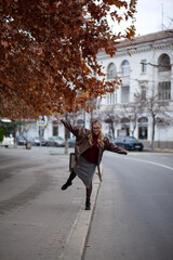 a beautiful stylish girl dressed in urban style of clothes walks around the city in cloudy weather