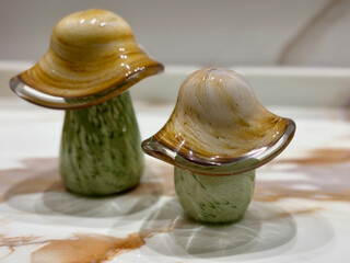 Two glass mushroom sculptures with green bases and brown beige caps