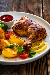 Oven roasted chicken thigh with fried potatoes and fresh salad on wooden table	