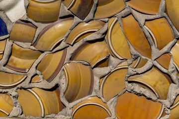 Fototapeta premium the facade of the building plastered with crushed and broken old plates. an original idea for construction and home decor. texture and background of plaster, concrete with crushed plates on the wall