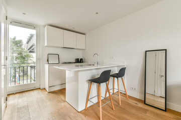 A stylish minimalist kitchen featuring sleek cabinetry and modern appliances, complemented by natural light and a clean aesthetic from the hardwood floor.