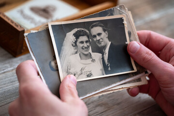 Close-up male hands sort through black and white photographs, evoking nostalgia and cherished...