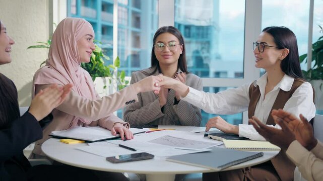 Happy multiethnic women females diversity team five girls coworkers businesswomen business colleagues shaking hands handshake gesture cooperation deal partnership teamwork inside office meeting room
