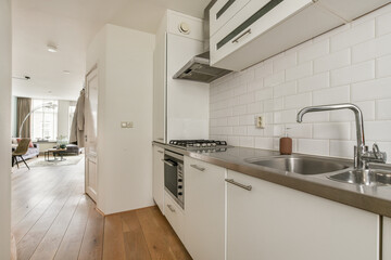 A sleek, modern kitchen featuring minimalist design elements with an open layout, stylish cabinetry, and natural wood flooring that enhances the space's elegance.