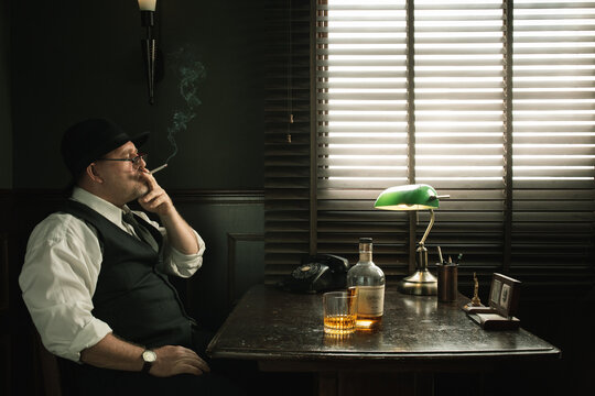 smoking detective.  NO LOGOS OR TRADEMARKS!  SELF MADE LABELS!  Portrait of a man in fedora is smoking in vintage detective office. 