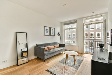A stylish modern living room featuring a grey sofa, a round coffee table, and minimalist decor elements that create a welcoming atmosphere.