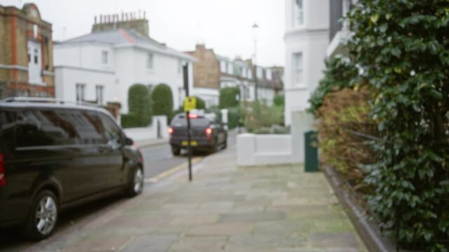 Blurred london street scene featuring defocused cars and autumn foliage in an outdoor uk setting with a bokeh effect on a cloudy winter day.
