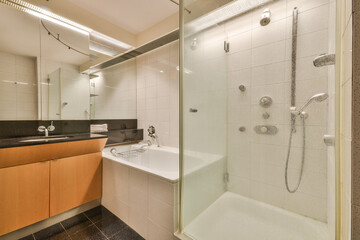 A stylish bathroom featuring a shower and bathtub, complemented by modern sink fixtures and elegant lighting. The design employs minimalist aesthetics.