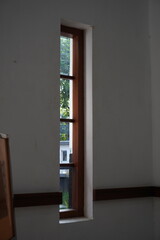 A long window with wooden lines against a white wall exposed to the morning sunlight