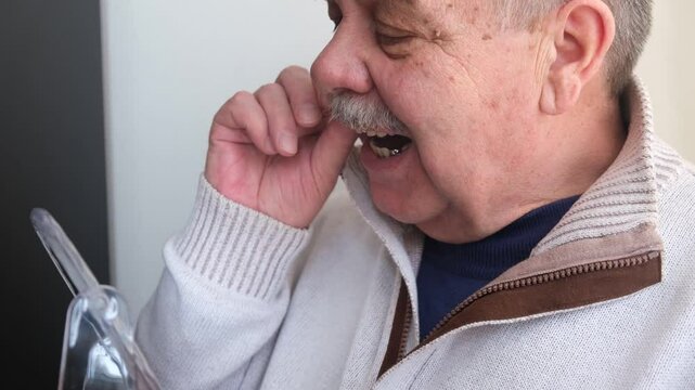 An elderly man holds a denture in his hands. The concept of stomatology and prosthetics. A dental prosthesis. Dentures on hooks