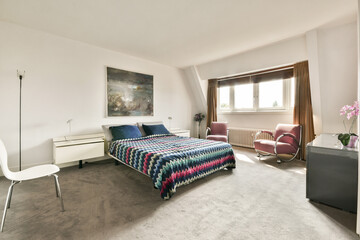 A stylishly designed bedroom featuring a cozy bed with vibrant, striped bedding, contemporary furniture, and elegant decor.