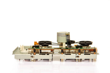 Close-up of the magnetic tape drive mechanism of an old double-cassette tape recorder on a white...