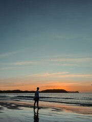 Fototapeta premium Silhouette of man on the beach at colorful sunset