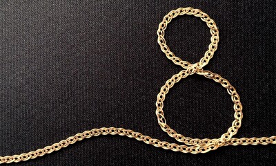 Stylish dark card for Women's Day March 8, figure eight made of gold chain on a textured black background. Celebrating International Women's Day. Concept March 8.