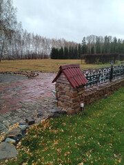 Autumn landscape with brickwork foundation of wrought iron fence. Late autumn, rainy day.