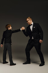 Father and son share a confident moment in elegant tuxedos at a studio setting