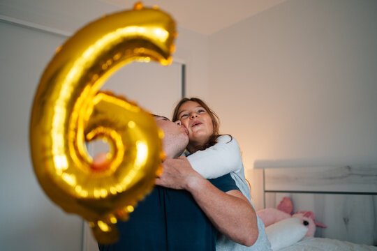 Caucasian adult couple celebrating with gold balloon indoors