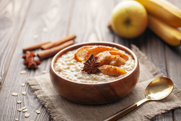 Oatmeal porridge with caramelised apples and bananas in bowl on the table. Homemade healthy breakfast