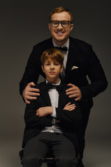 Dapper father and son share a moment in elegant tuxedos at the studio
