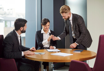 Group of business people or company employees sitting at the desk on workplace, reaching agreement and going signing a contract making a deal. Coworkers having a meeting in office.