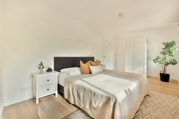 A well-designed minimalist bedroom featuring a bed with neutral bedding, a nightstand, and green plants, emphasizing clean lines and a serene atmosphere.