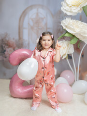 Generated A little girl in pink clothing celebrates in a fairy-tale setting with pastel decorations, a large pink balloon in the shape of a two, and white flowers, radiating joy and innocence.